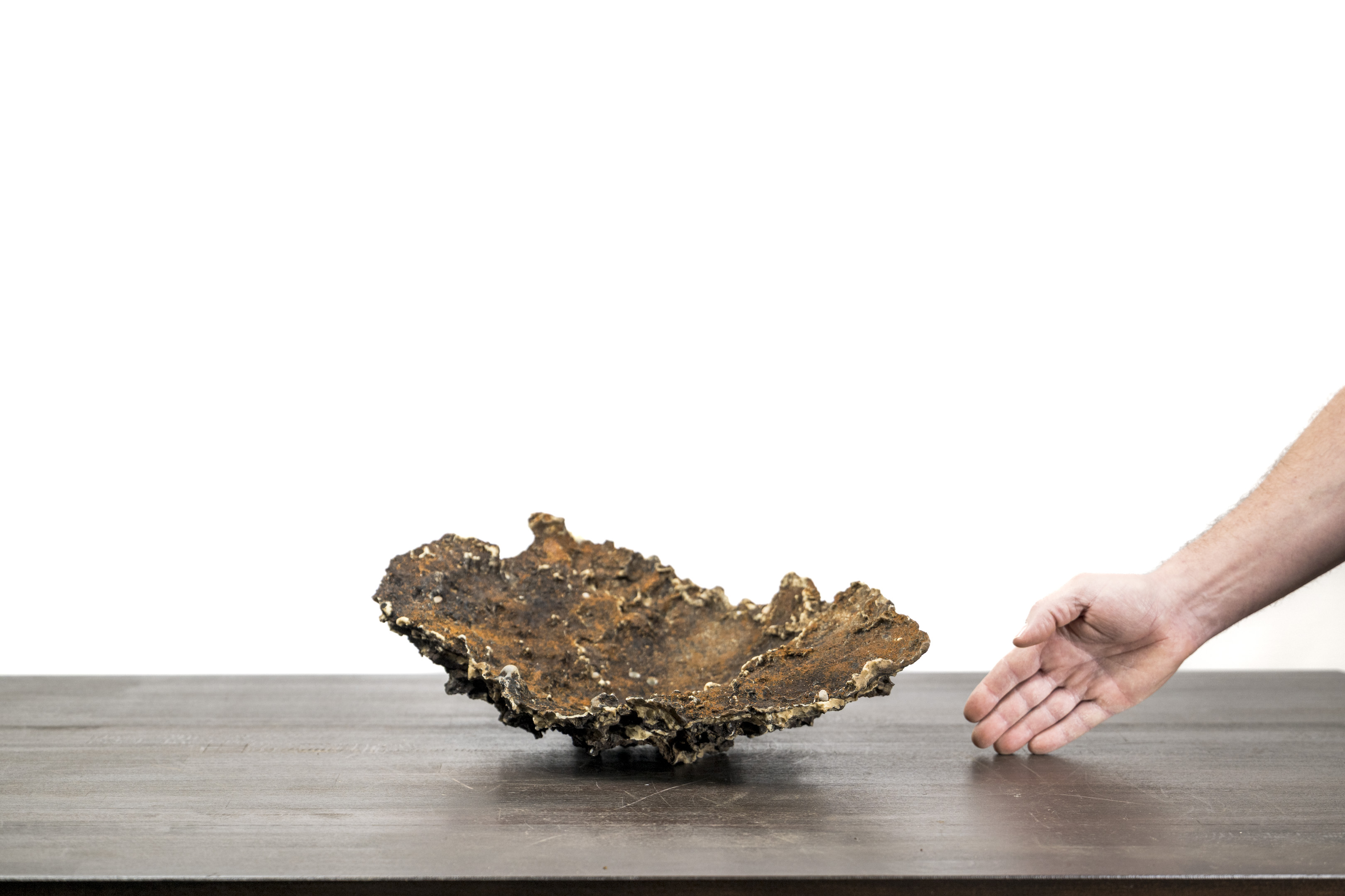 Slab No. 57 on a tabletop, showing its inner surface with a hand alongside on the right